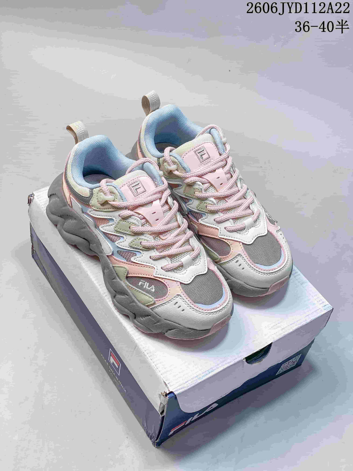 Pair of pastel pink, grey, and off-white FILA FUSION Arceus chunky sneakers on a shoebox.