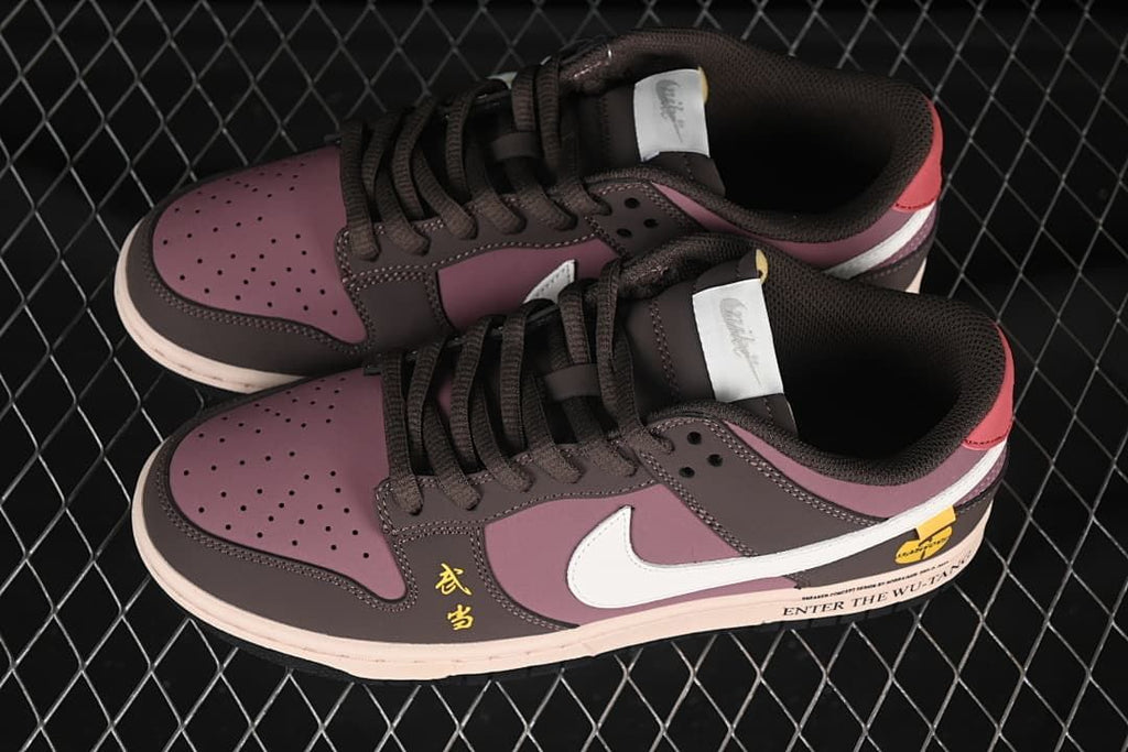 Overhead view of a pair of mauve and dark brown Nike SB Dunk Low sneakers with white Swooshes and Wu-Tang-themed details