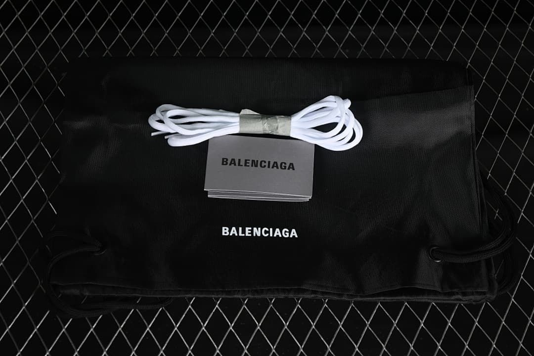 Black drawstring bag, spare white laces, and branded booklet shown with the sneakers.