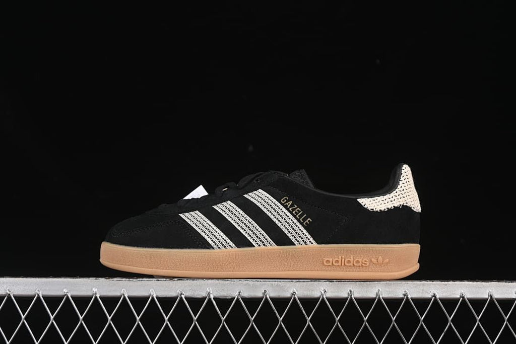Side view of black Gazelle Indoor low-top sneakers with cream stripes and a gum-colored sole.