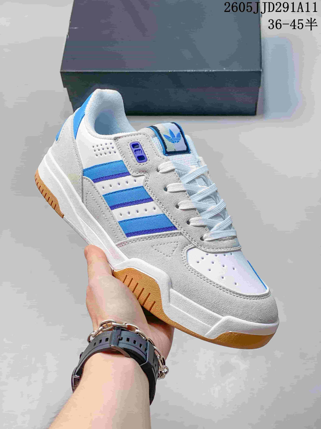 Close view of a white and light gray Tekkira Cup sneaker with blue side stripes and a gum-colored outsole