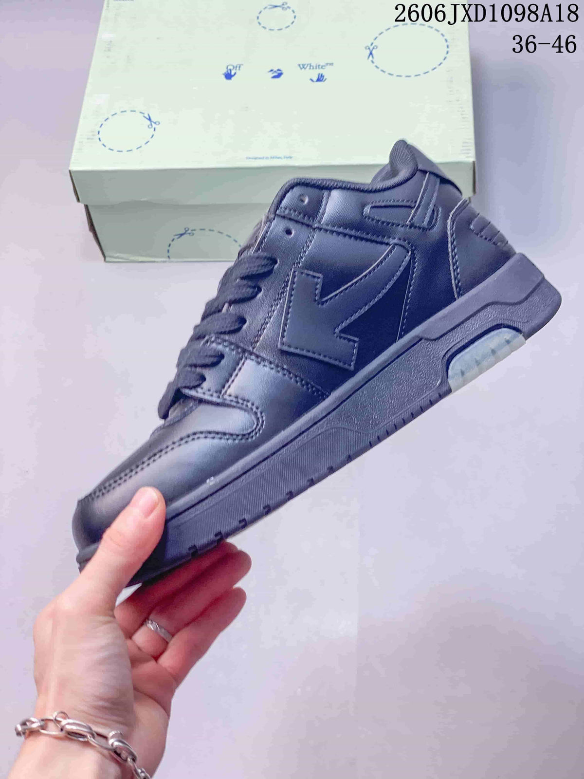 Side profile of the dark low-top sneaker with a large logo motif and chunky sole