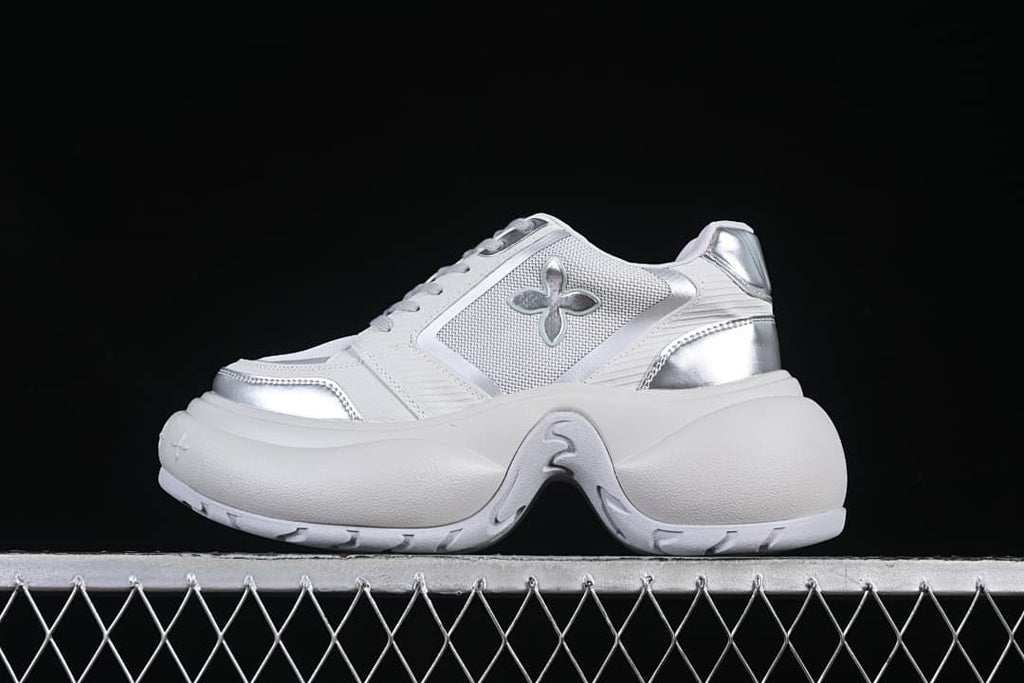 Side view of a gray-and-silver sneaker with a four-petal emblem