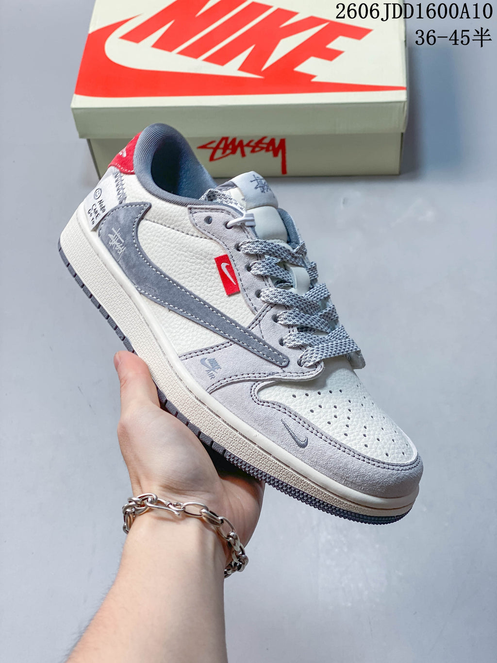Angled side view of the off-white and grey low-top sneaker with red accents.
