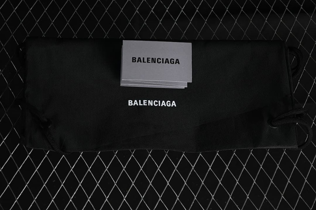 Black branded drawstring shoe bag and grey card pictured with the sneakers