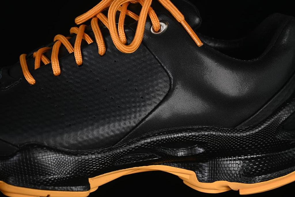 Close-up of black upper, orange laces, and textured side panel