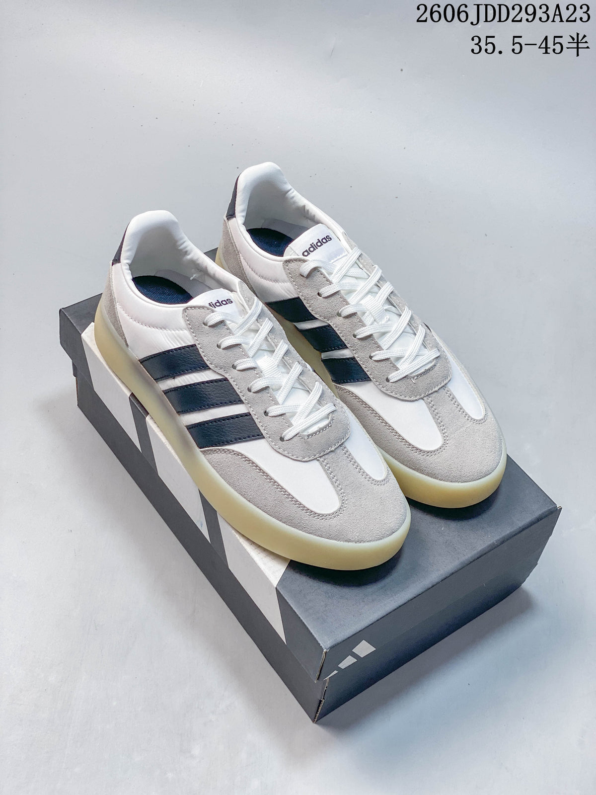 Pair of white and gray Adidas Barreda Decode sneakers with dark side stripes and a gum-look sole.