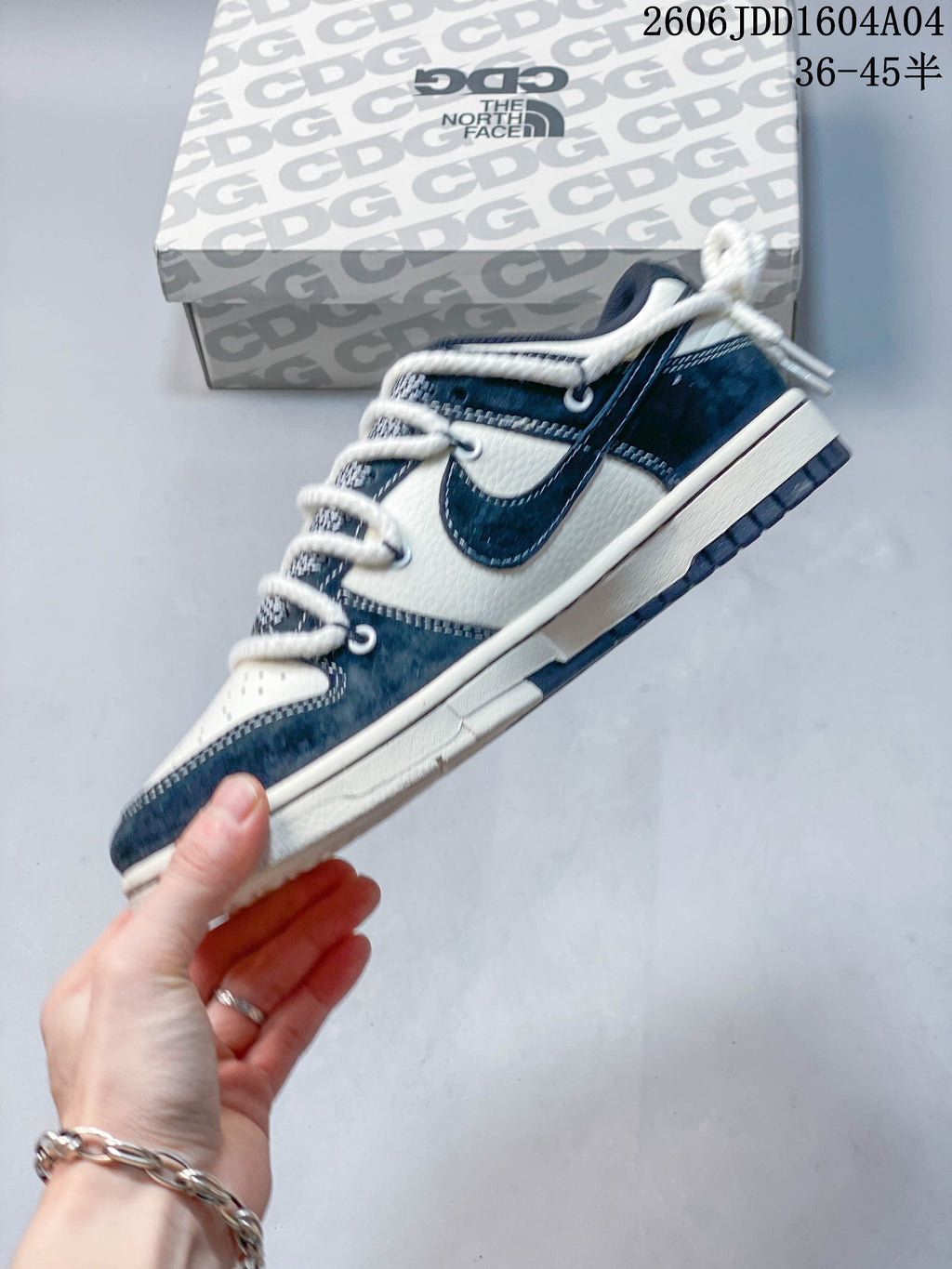 Side profile showing navy panels, off-white sections, and a swoosh-shaped detail.