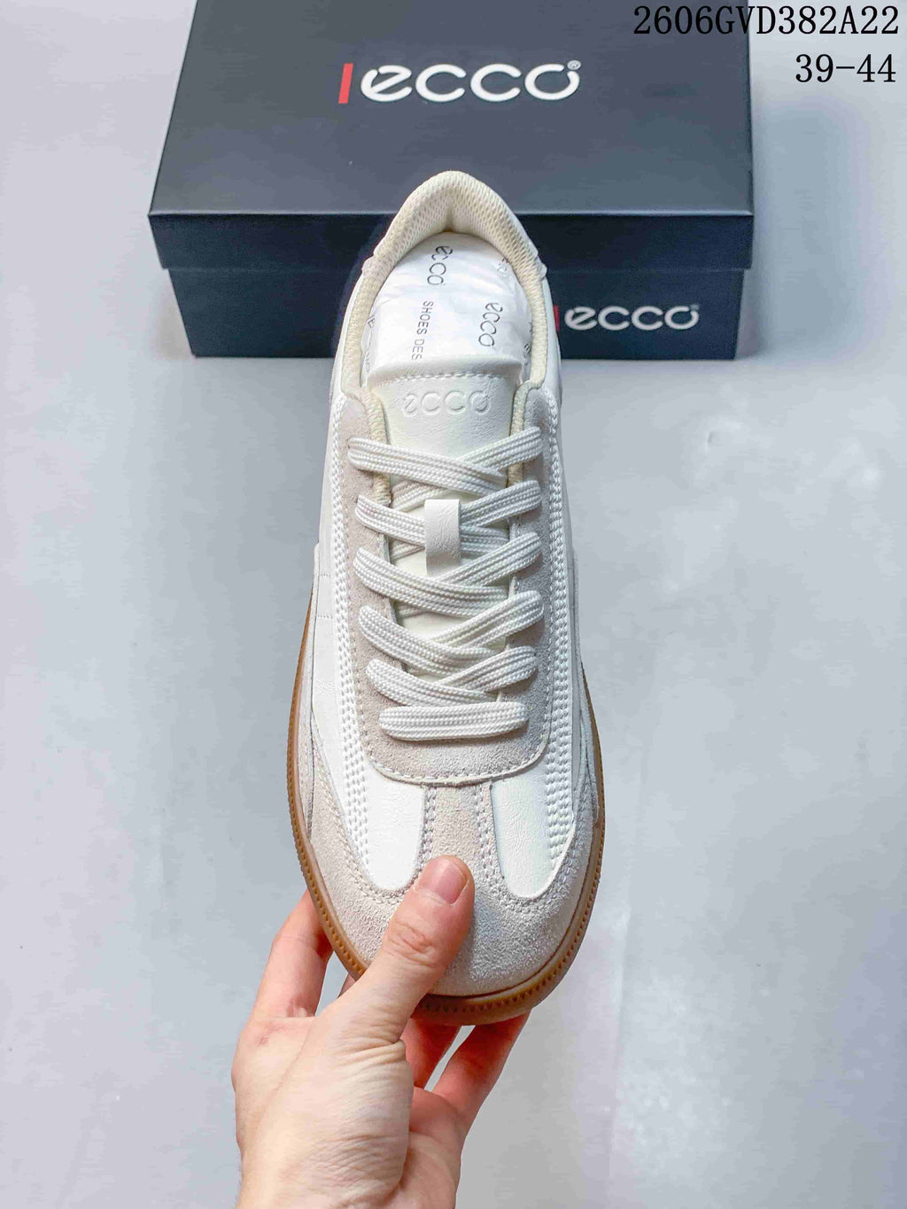 Top view of a light-colored lace-up sneaker with contrasting textured panels