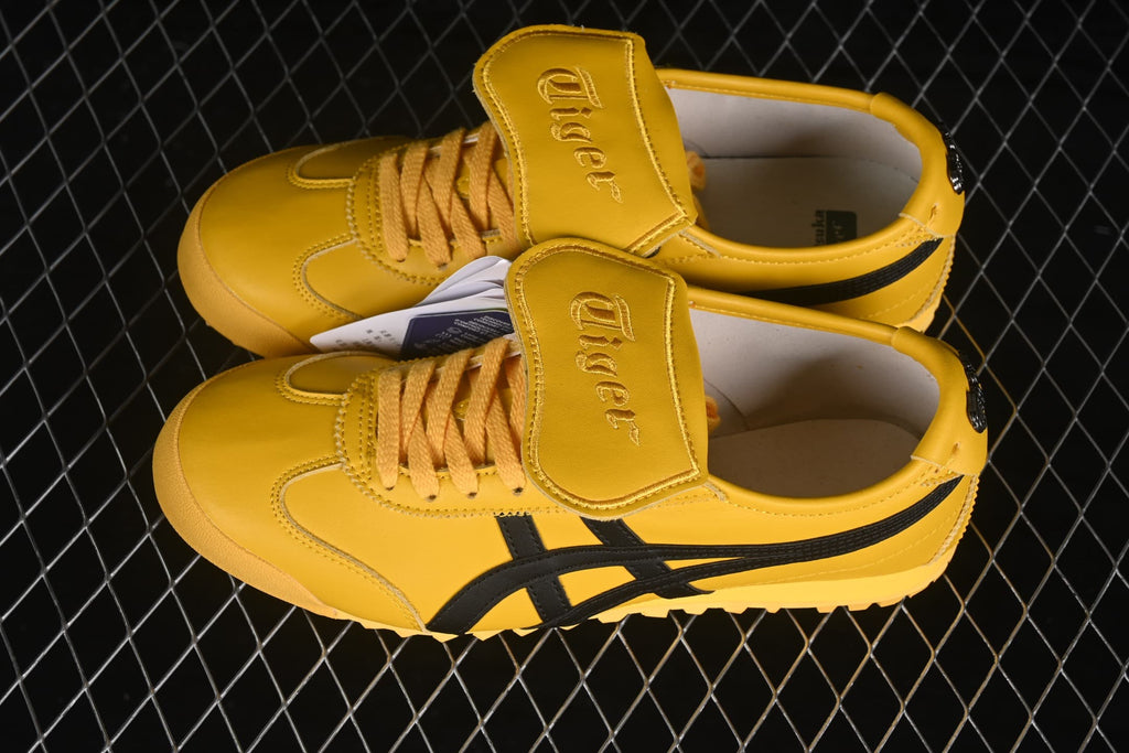 Angled top view showing the yellow upper, black side stripes, laces, and tongue flaps