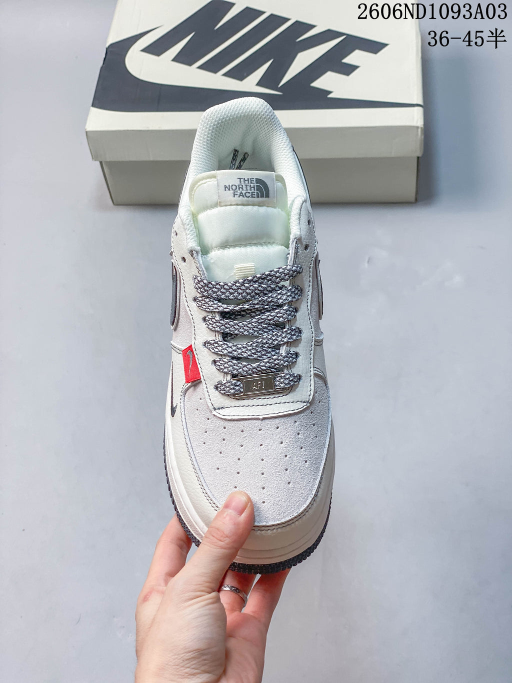 Front view of the sneaker showing perforated toe, patterned laces, and red accent