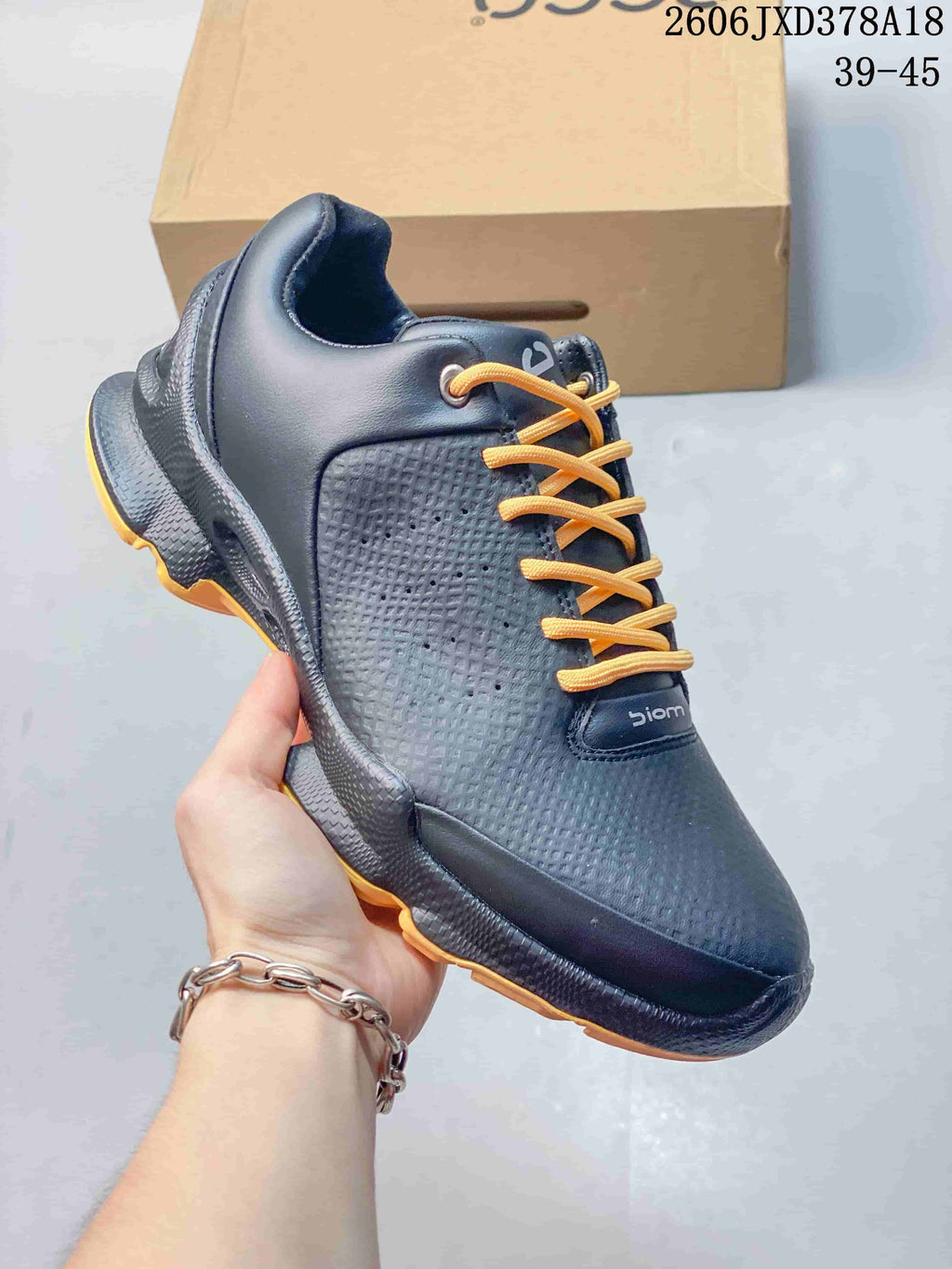 Angled side view showing the textured upper and orange accents on a black ECCO BIOM sneaker.
