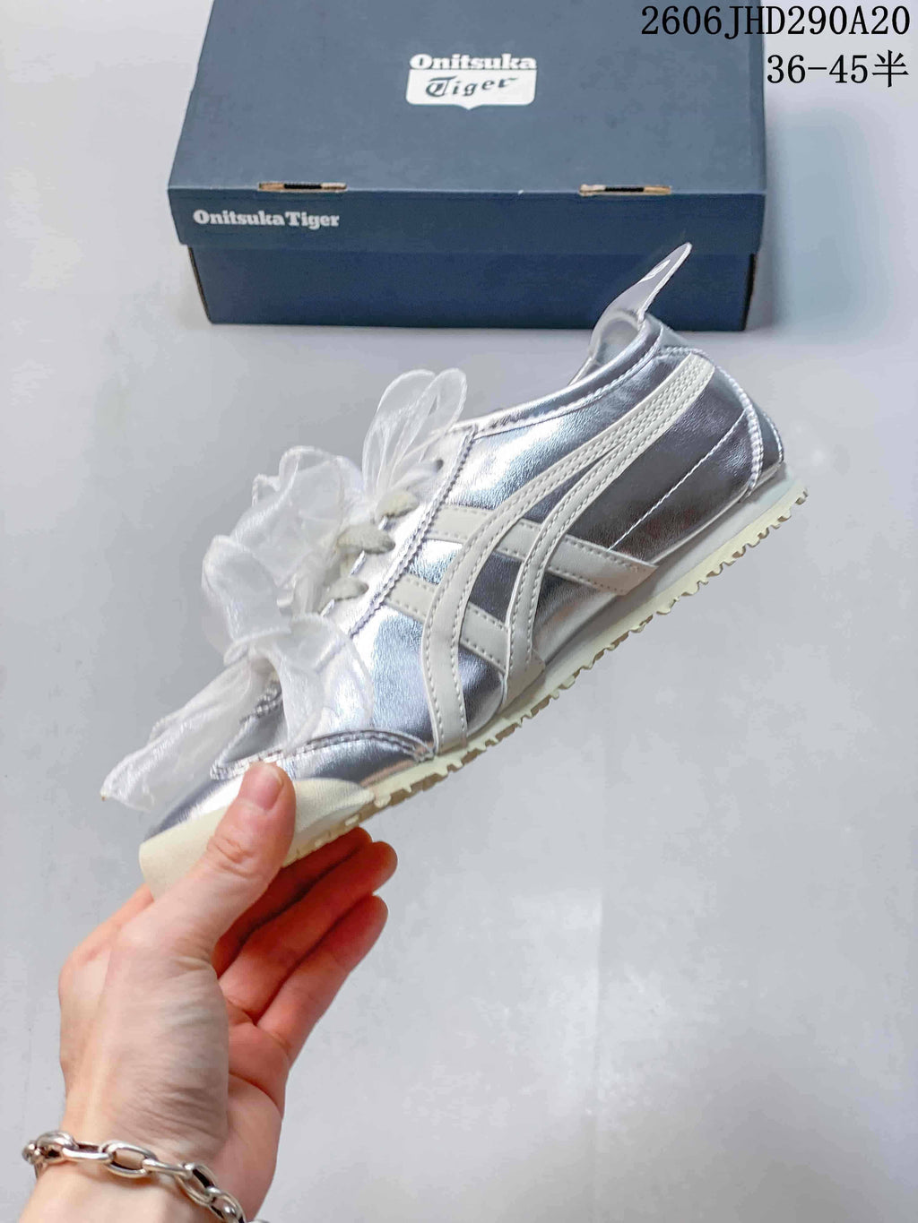 Side view of a metallic silver Onitsuka Tiger sneaker with cream stripes and sheer ribbon laces