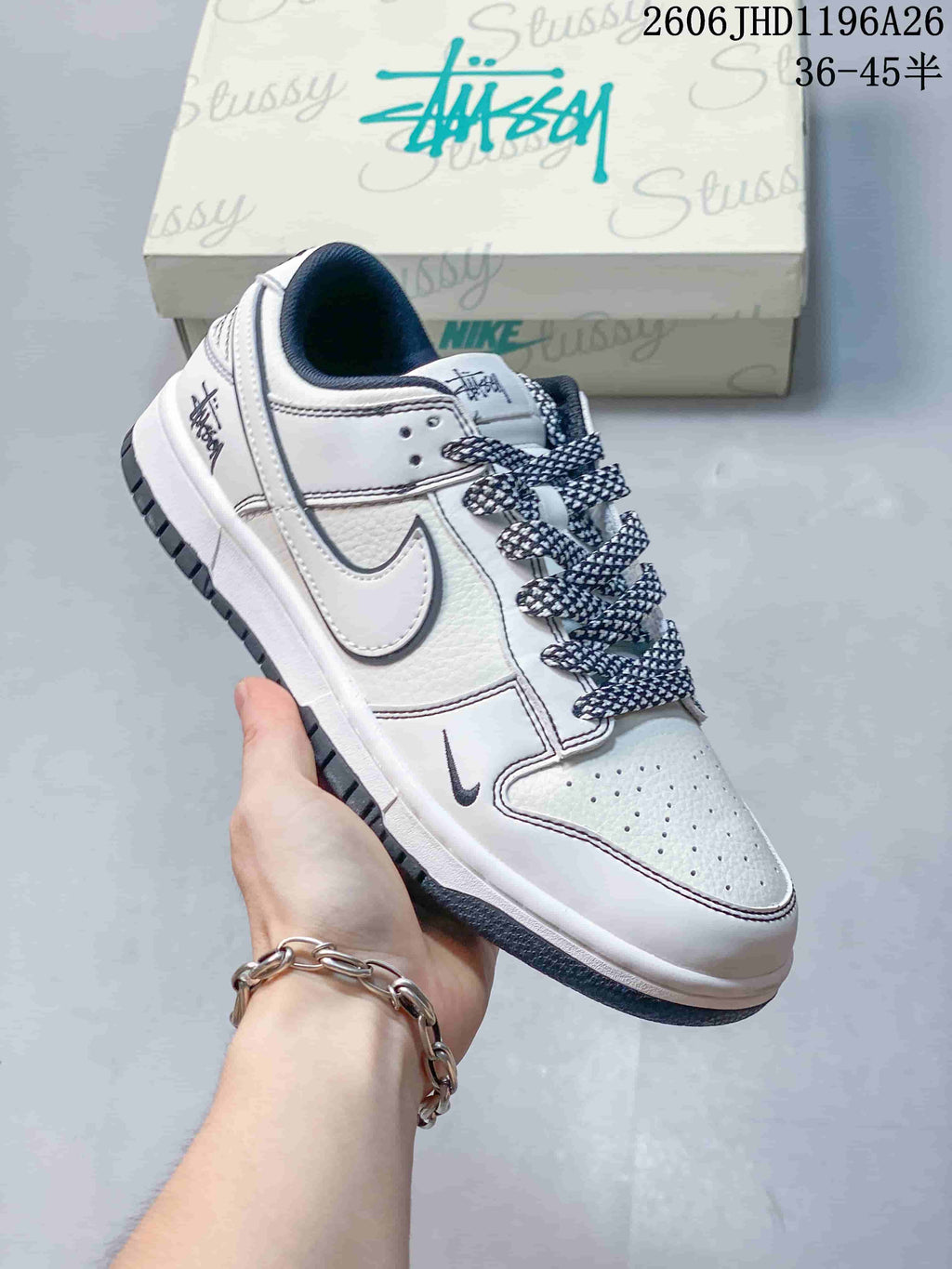 Close view of a white low-top sneaker with patterned laces, side logo, and dark outsole.