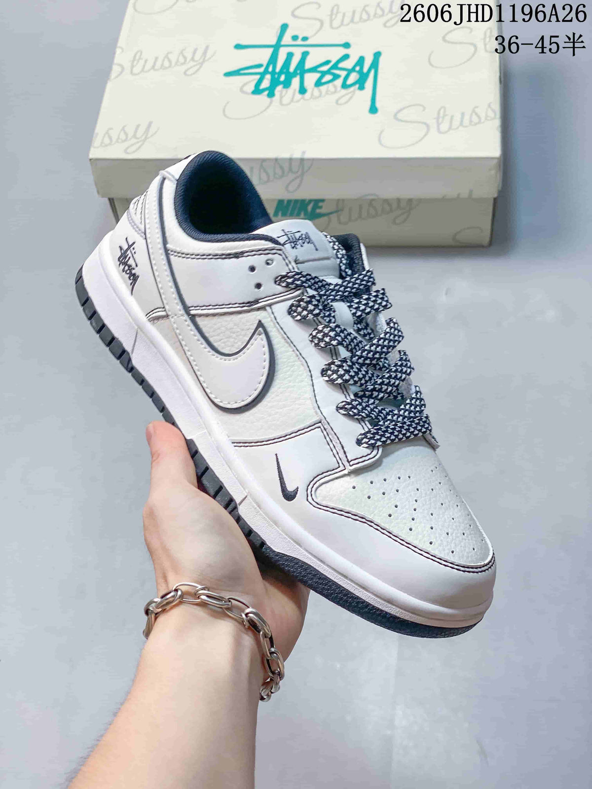 Close view of a white low-top sneaker with patterned laces, side logo, and dark outsole.