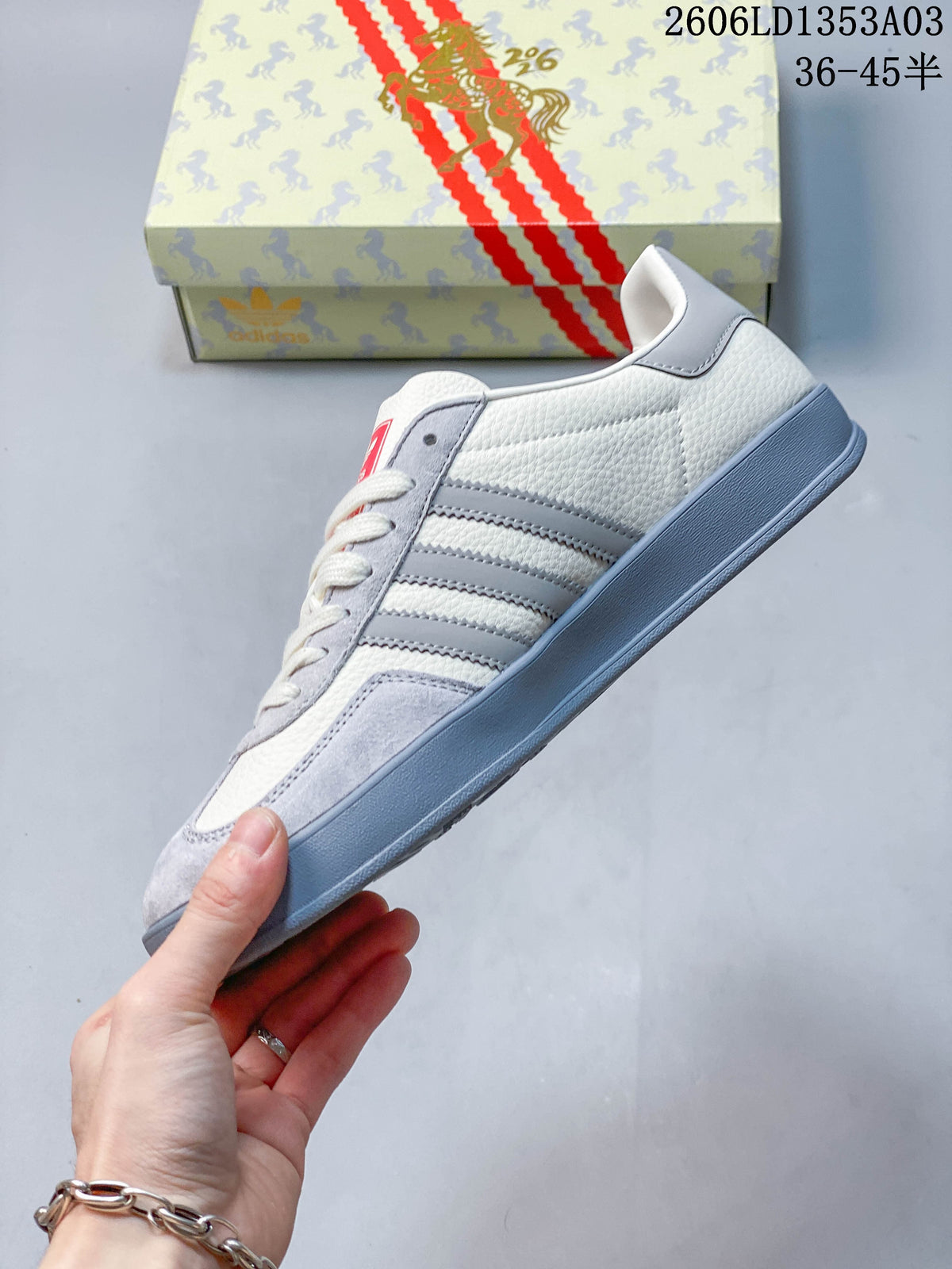 Side profile of a white and grey low-top sneaker with three side stripes