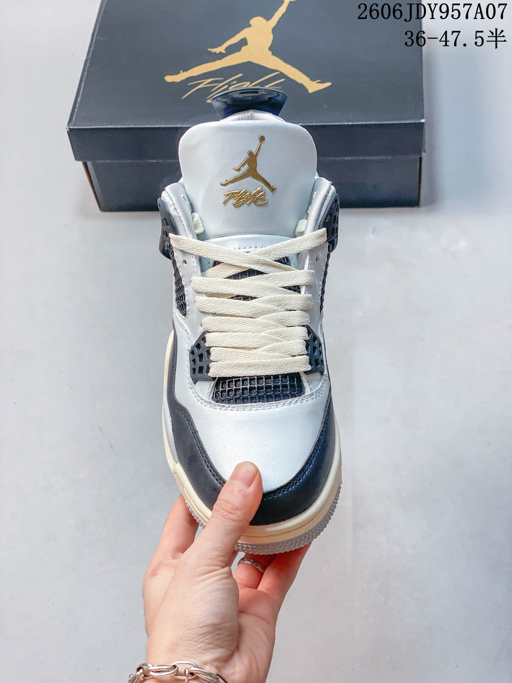 Front view of a white and dark-panel Jordan 4 sneaker