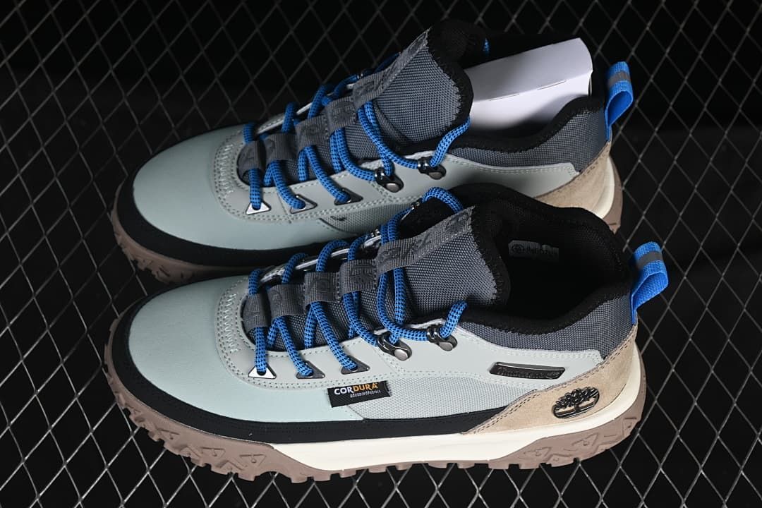 Pair of light grey and tan Timberland mid boots with blue laces