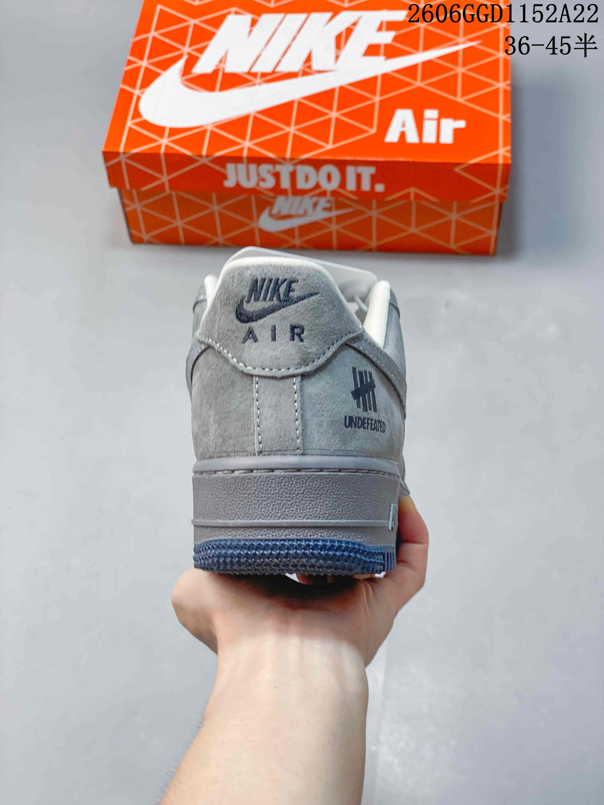 Rear view of the grey sneaker showing heel branding and a dark blue outsole