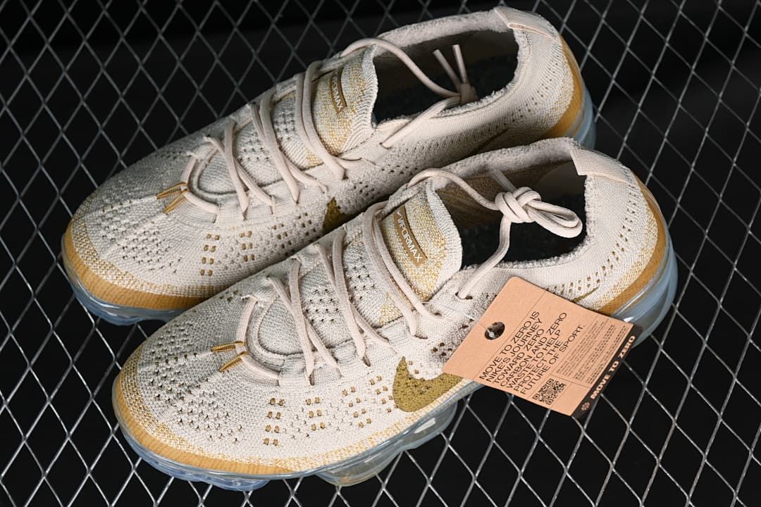 Pair of neutral and gold-toned sneakers shown from above at an angle.