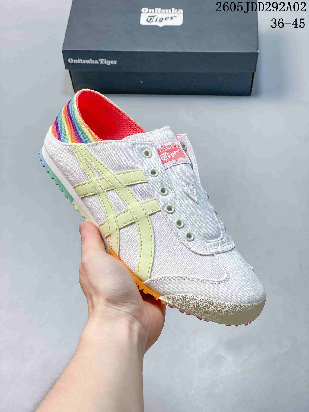 White slip-on sneaker with pale yellow side stripes and a multicolor heel panel