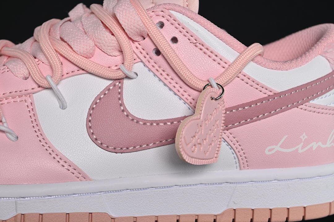 Close-up of the pink side swoosh, laces, and heart-shaped charm.