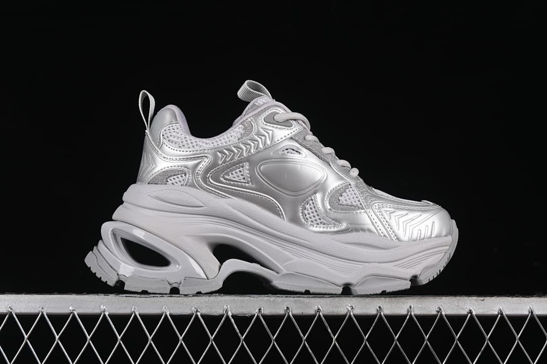 Side profile of a silver sneaker showing its chunky platform and open-shaped heel detail.