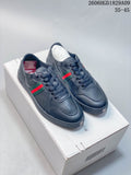 Pair of dark navy lace-up low-top sneakers with green-and-red side stripes, shown on a box.