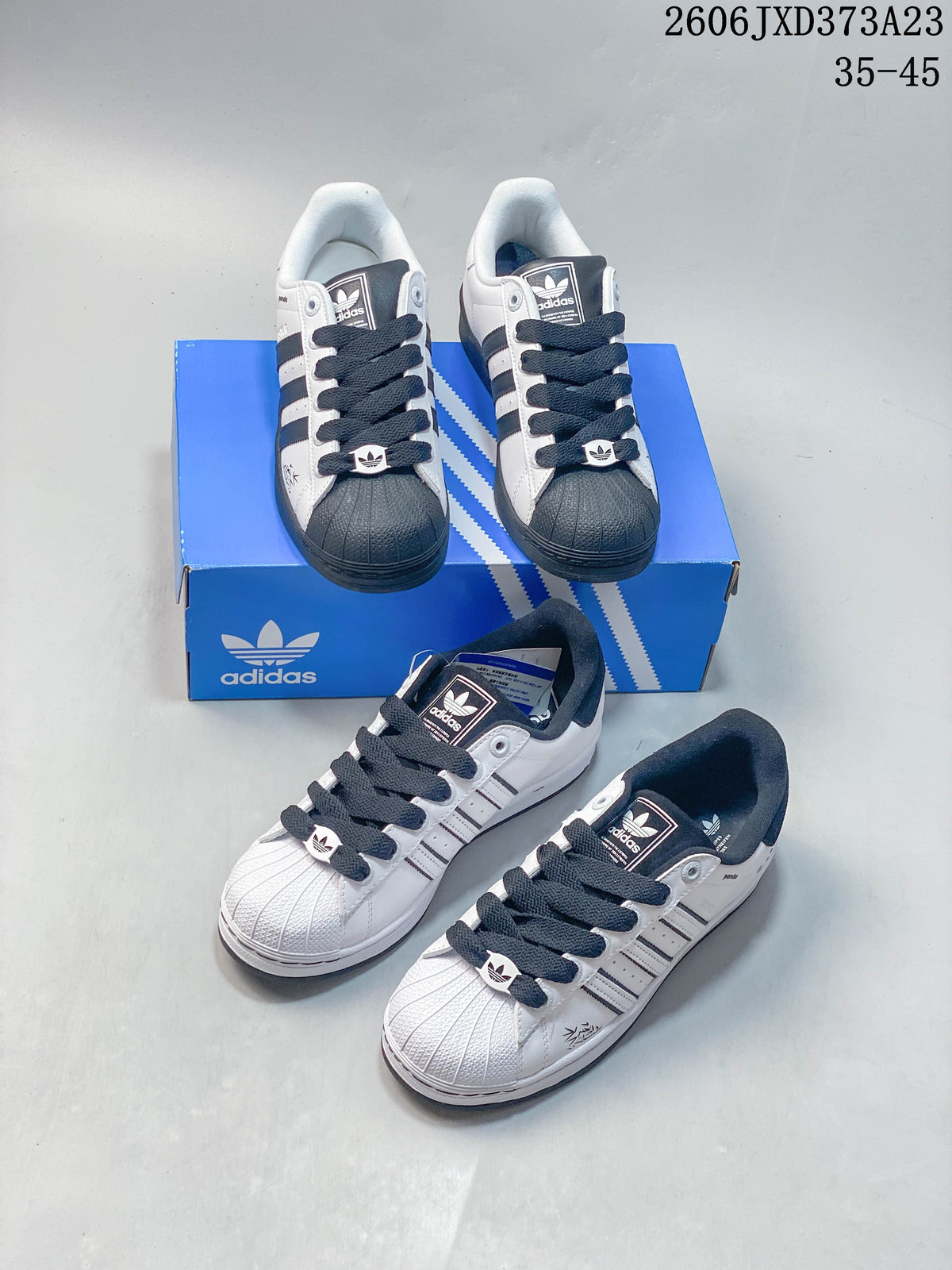 Several views of white and black Superstar sneakers arranged around a blue Adidas shoe box