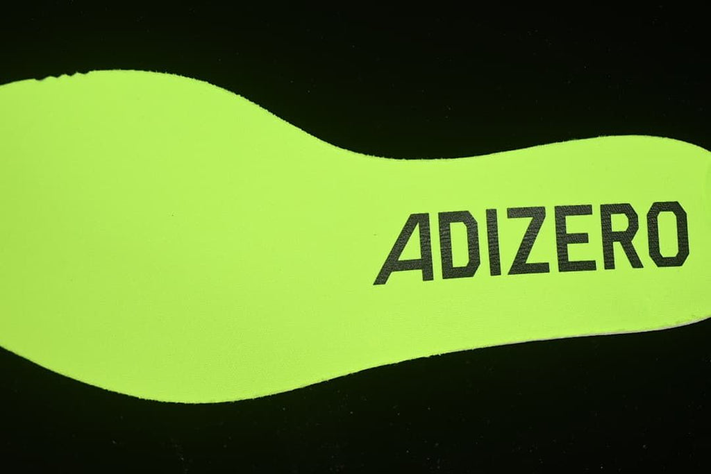 Close-up of neon yellow insole marked Adizero.