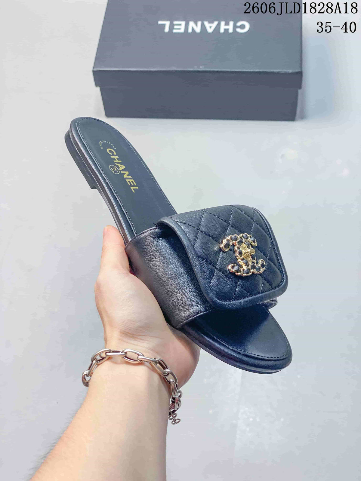 Angled view of a navy slide sandal with a quilted strap and gold-tone ornament