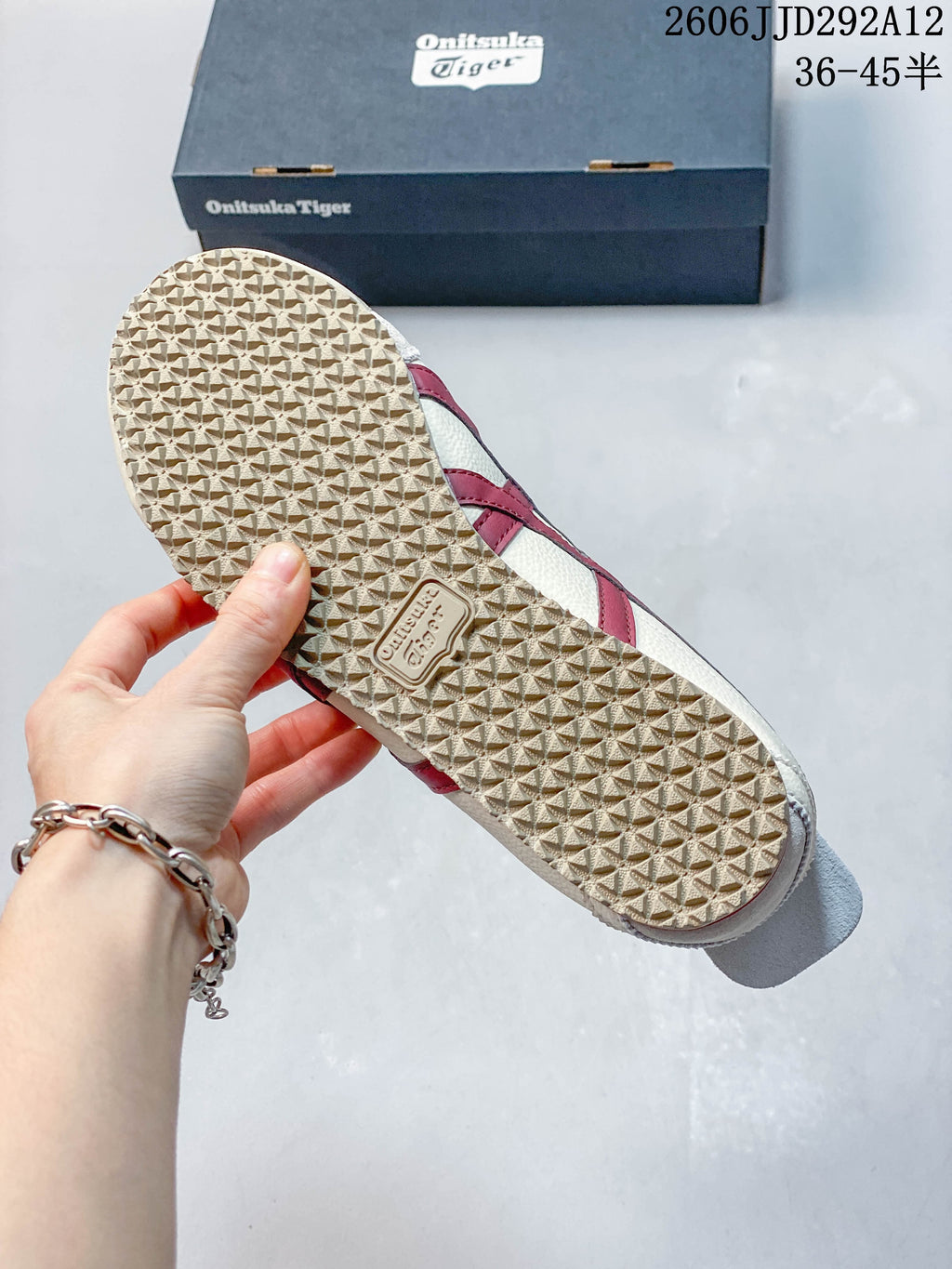 Close-up of the patterned outsole on a cream and burgundy sneaker