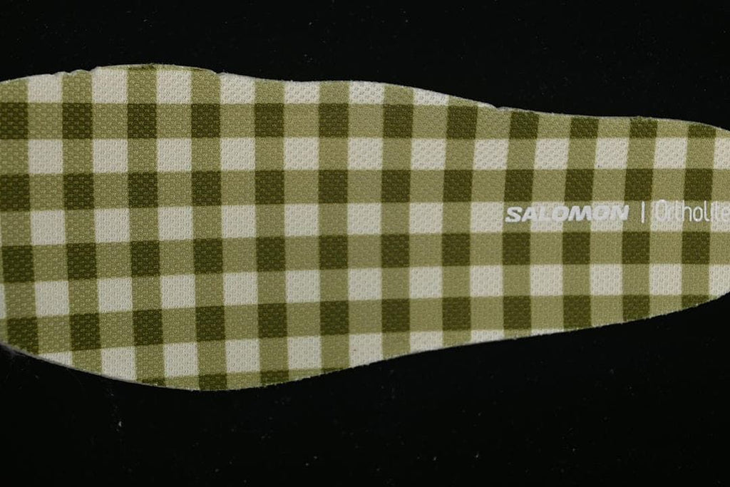 Close-up of a green-and-cream checkered shoe insert with Salomon branding.