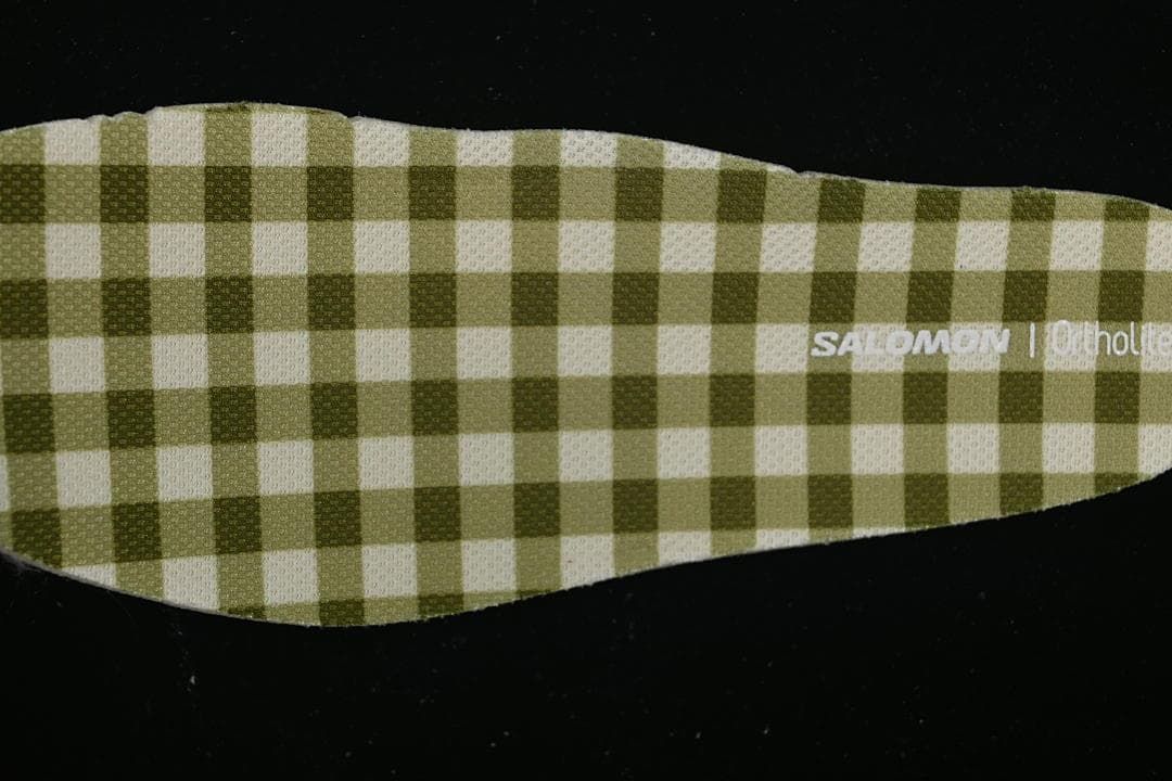 Close-up of a green-and-cream checkered shoe insert with Salomon branding.