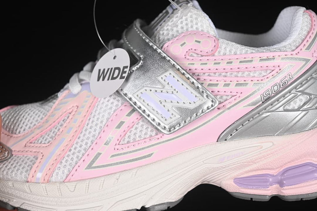 Close-up side view of pink and silver panels, the New Balance logo, and the fastening strap.