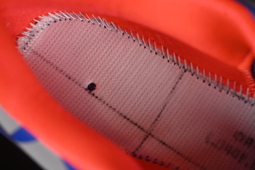 Close-up inside the shoe showing orange lining and stitched footbed