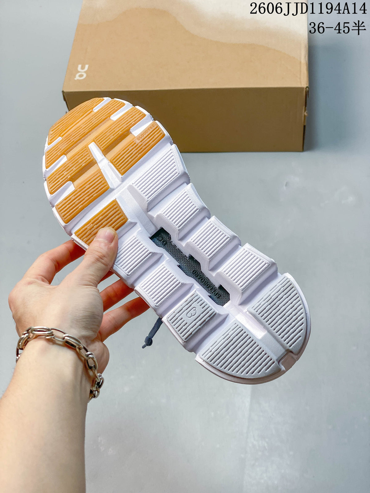 Underside of a blue sneaker showing a white segmented outsole and yellow-orange tread accents.