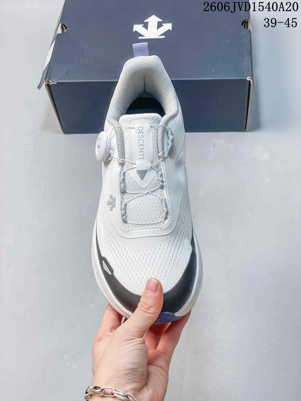 Top view of a white DESCENTE sneaker with a dial-style cable closure