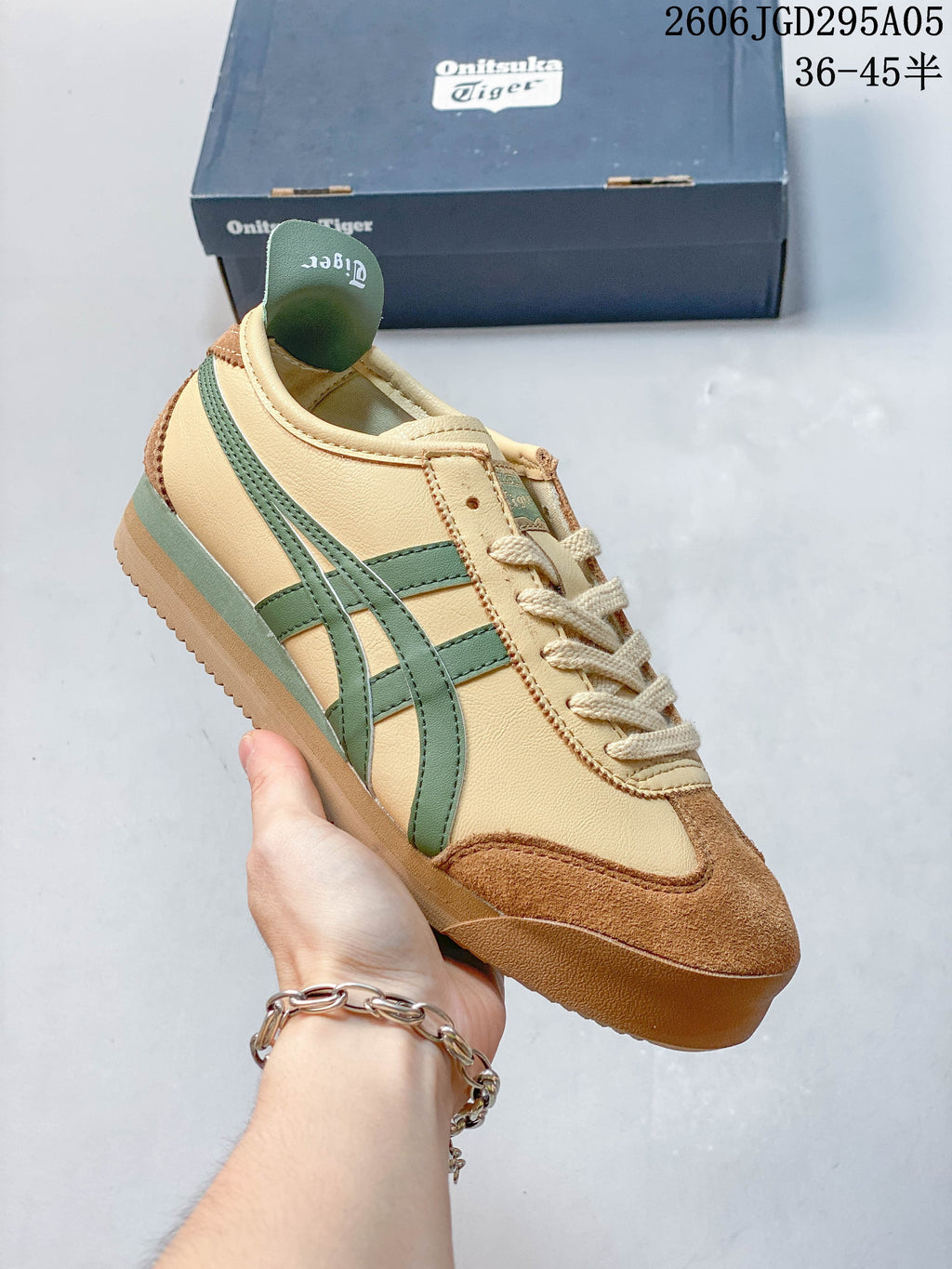 Cream low-top sneaker with green side stripes and brown toe overlays