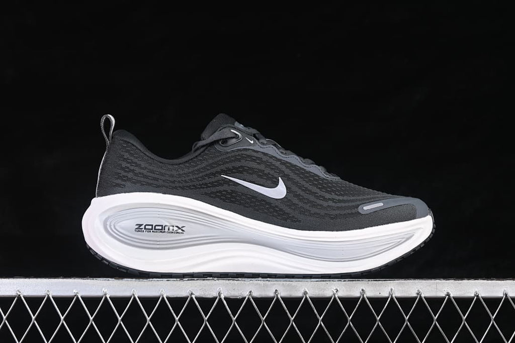 Side view of a dark Nike Vomero Plus running shoe with a white Swoosh and sculpted white midsole.
