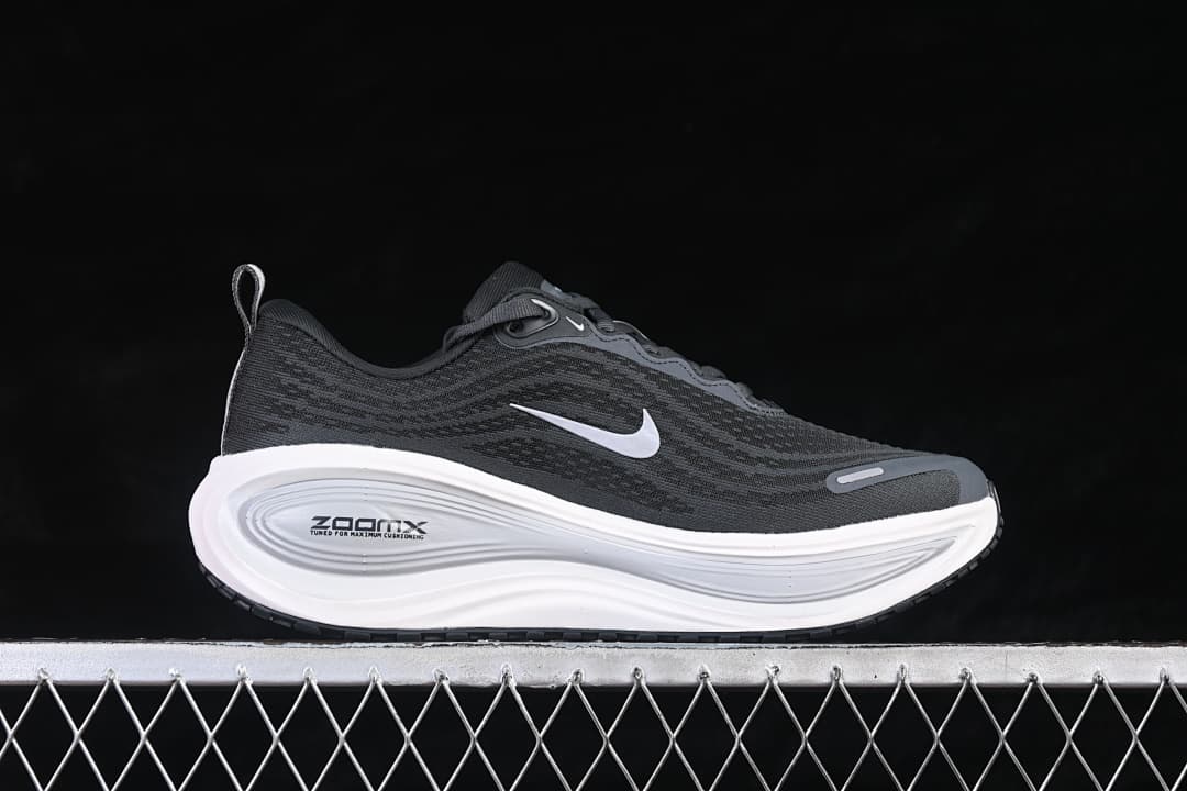 Side view of a dark Nike Vomero Plus running shoe with a white Swoosh and sculpted white midsole.
