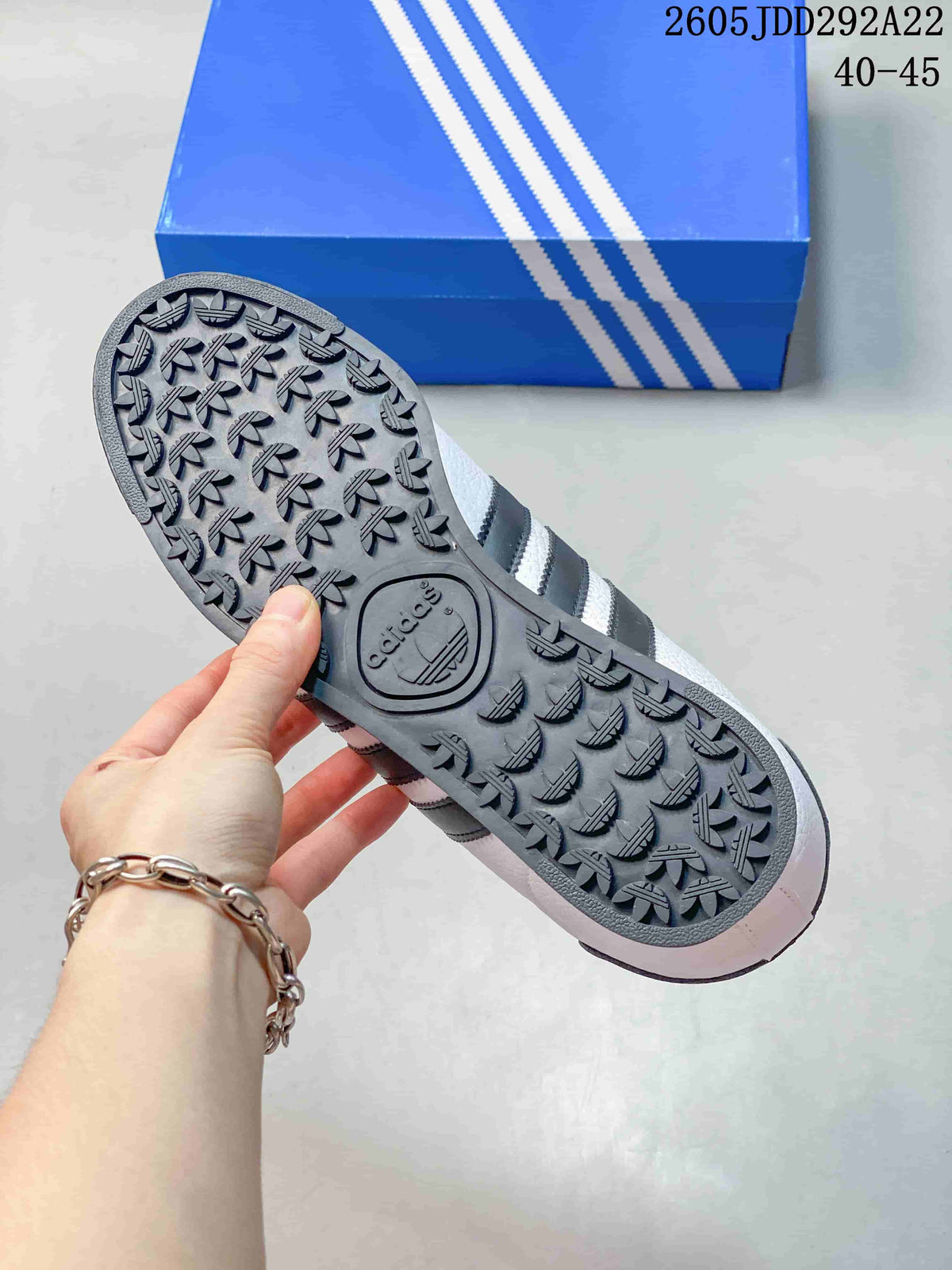 Outsole view of a white Adidas Samoa sneaker showing its dark patterned tread