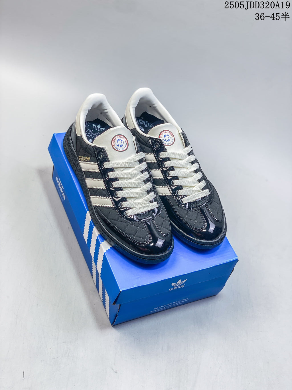 Pair of dark Adidas Gazelle Indoor sneakers with white stripes and cream laces on a blue shoe box.