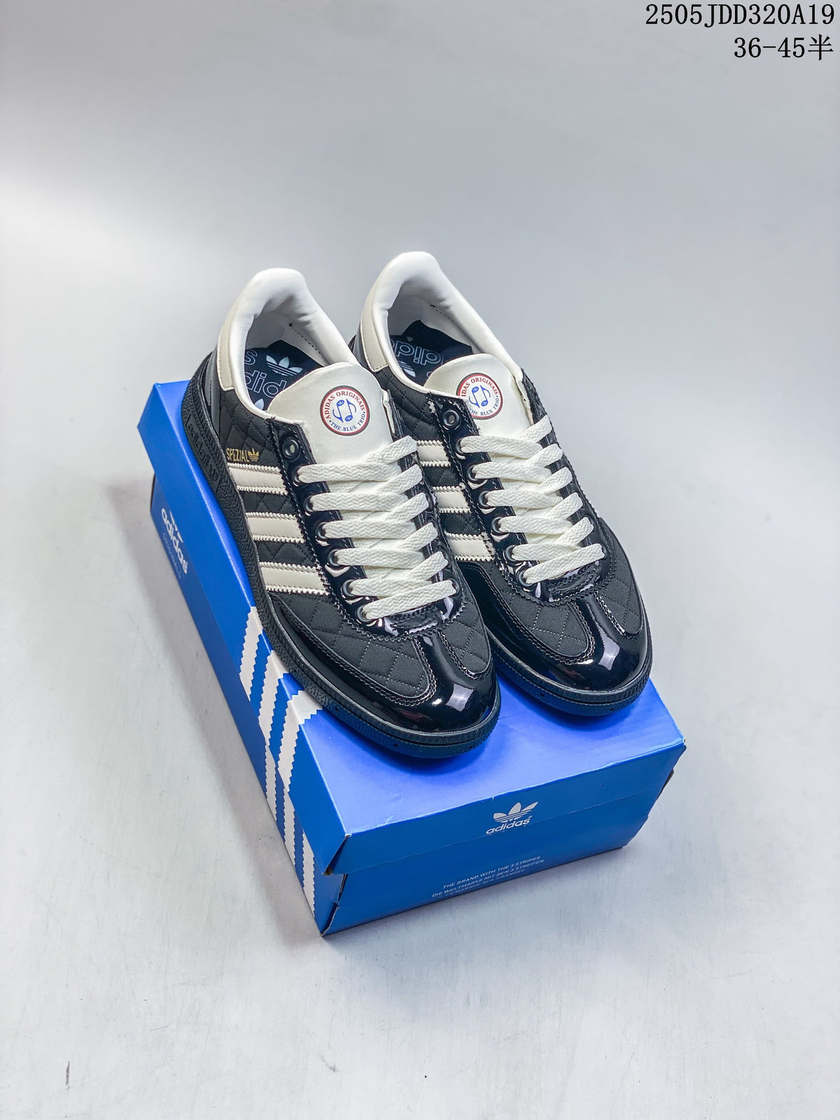 Pair of dark Adidas Gazelle Indoor sneakers with white stripes and cream laces on a blue shoe box.