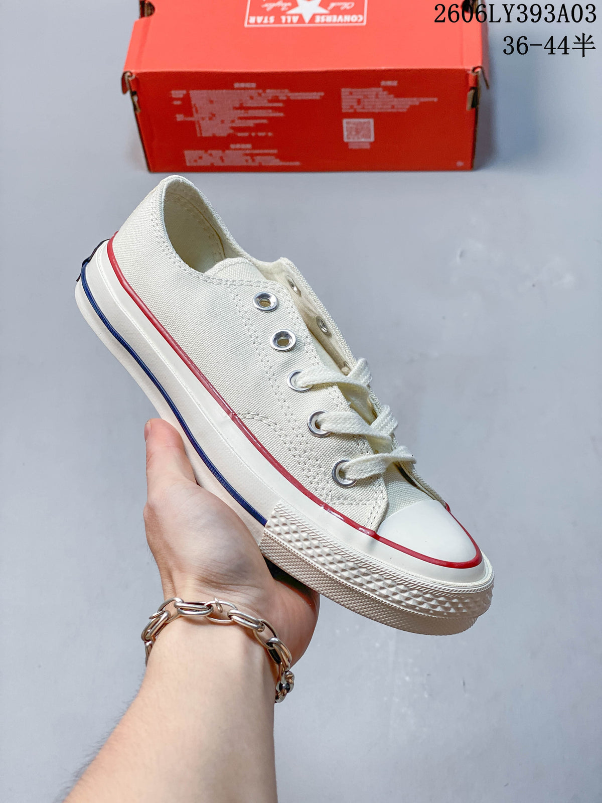 White low-top sneaker with red and blue stripes along the off-white sole
