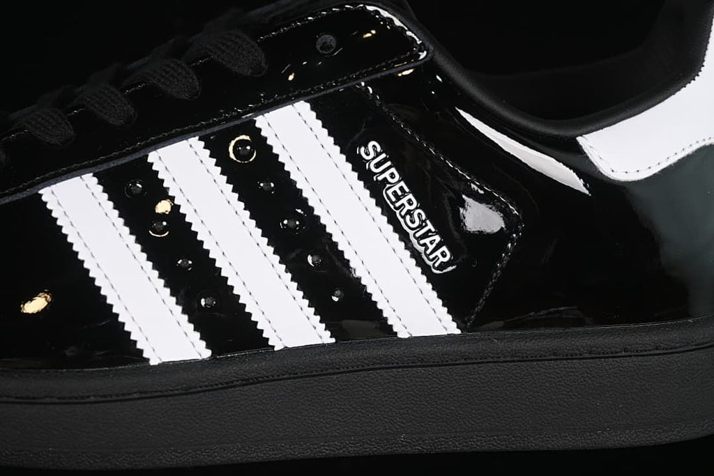 Close-up of the black upper, white side stripes, and Superstar lettering