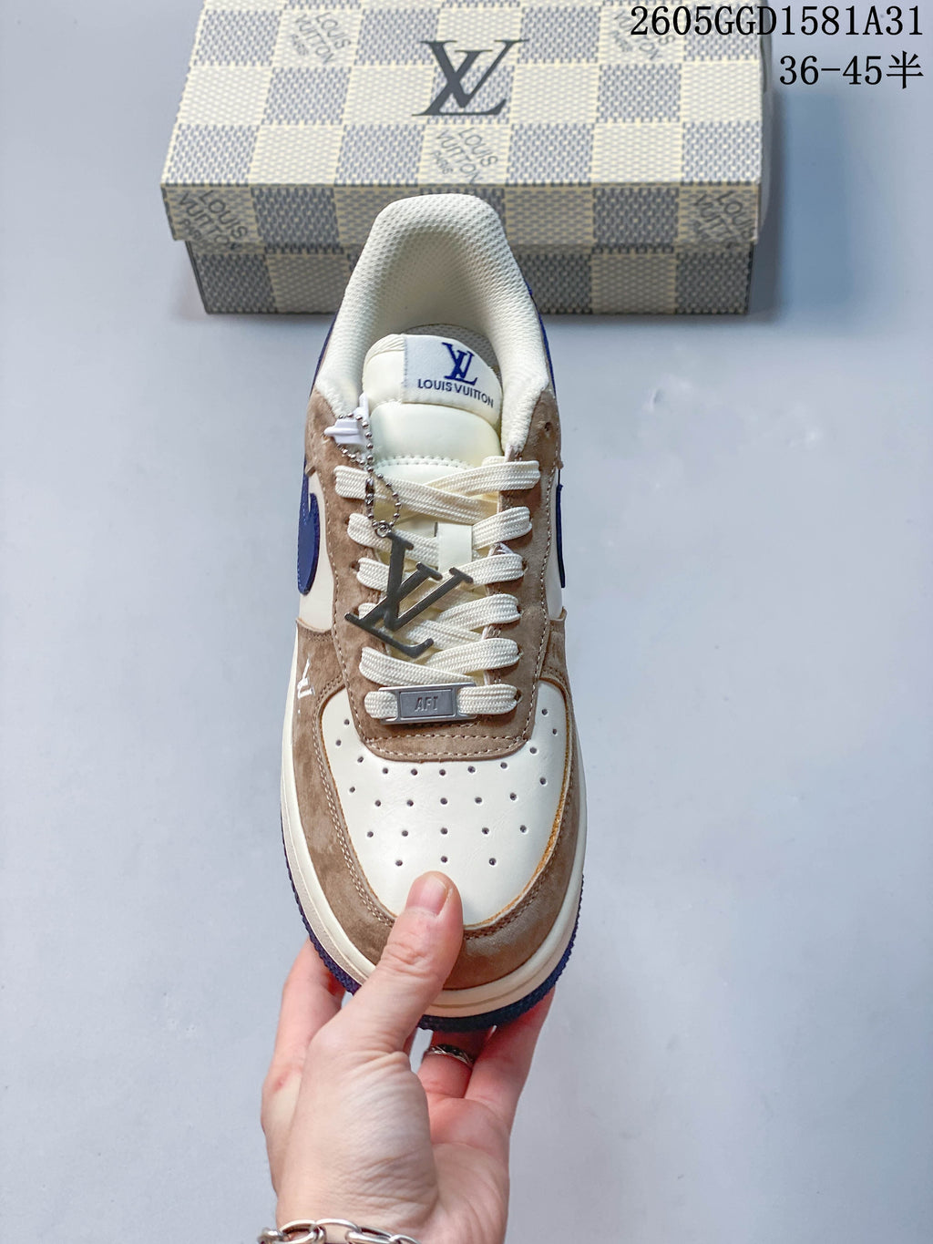 Top view of a cream and taupe sneaker with white laces and a metallic lace accessory