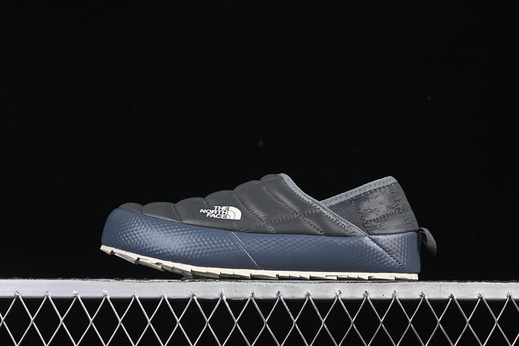 Side profile of a grey quilted The North Face mule with a blue sidewall and light outsole
