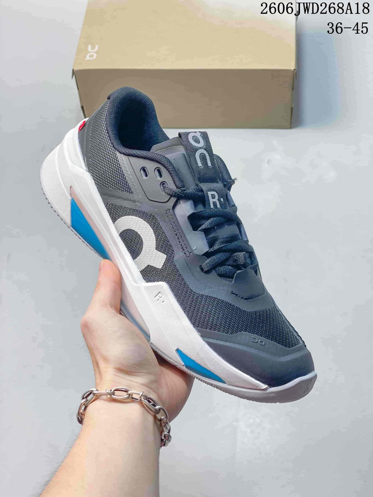 Angled side view of a gray On tennis shoe with white and blue details.