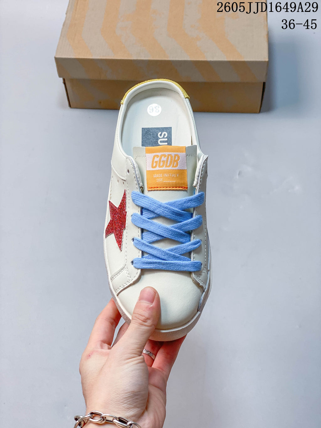 Top view of a white sneaker with blue laces and a red glitter side star